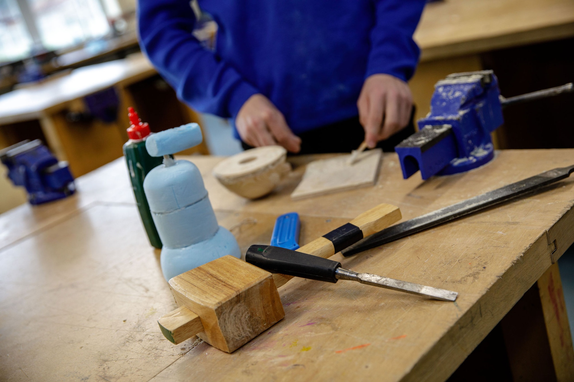 A child using woodworking tools at a school workbench